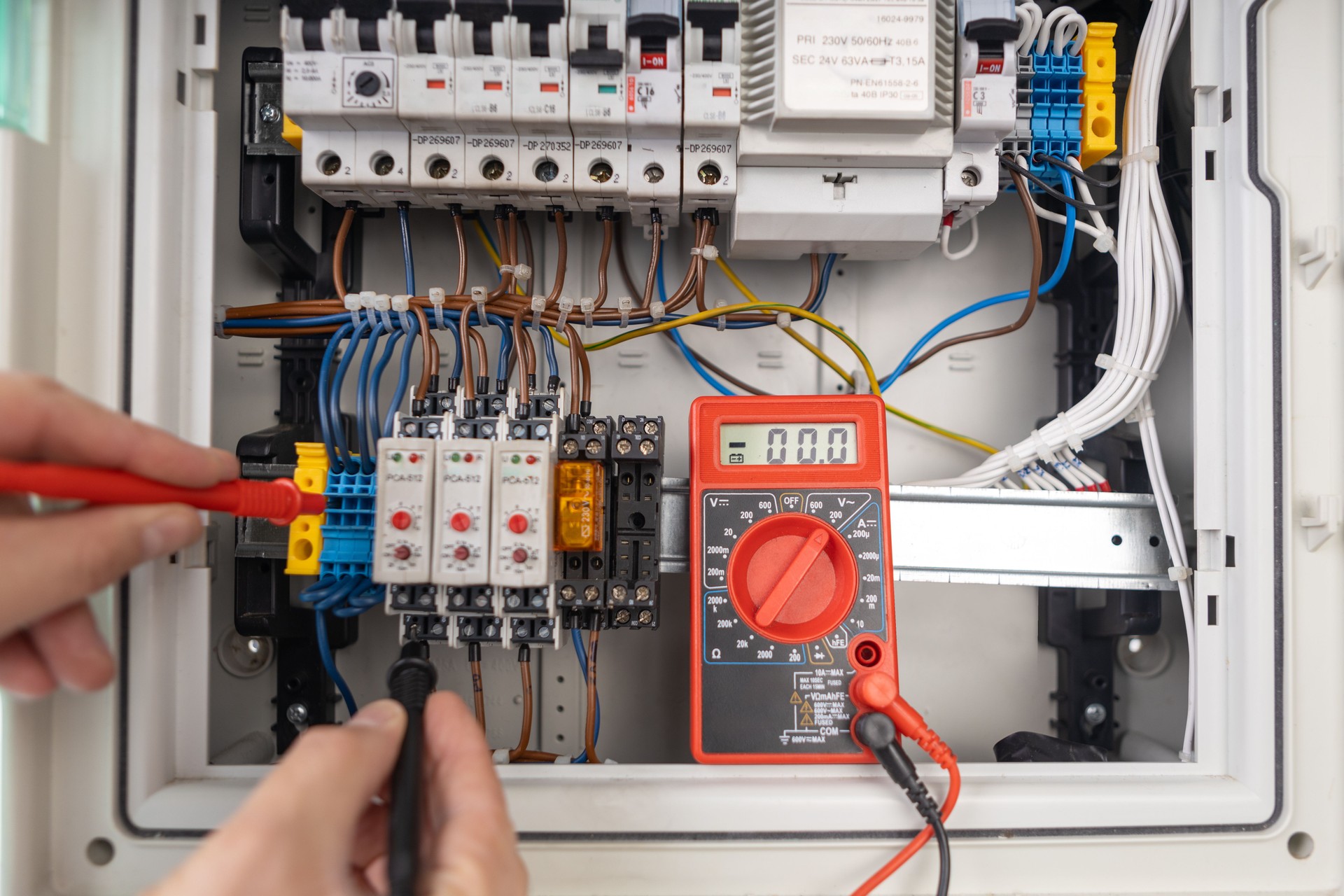 Technician Testing Electrical Circuit Board with Multimeter